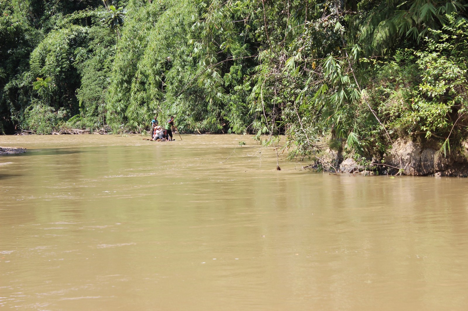 People travelling along a jungle river on a bamboo raft during NDP in the Jungle