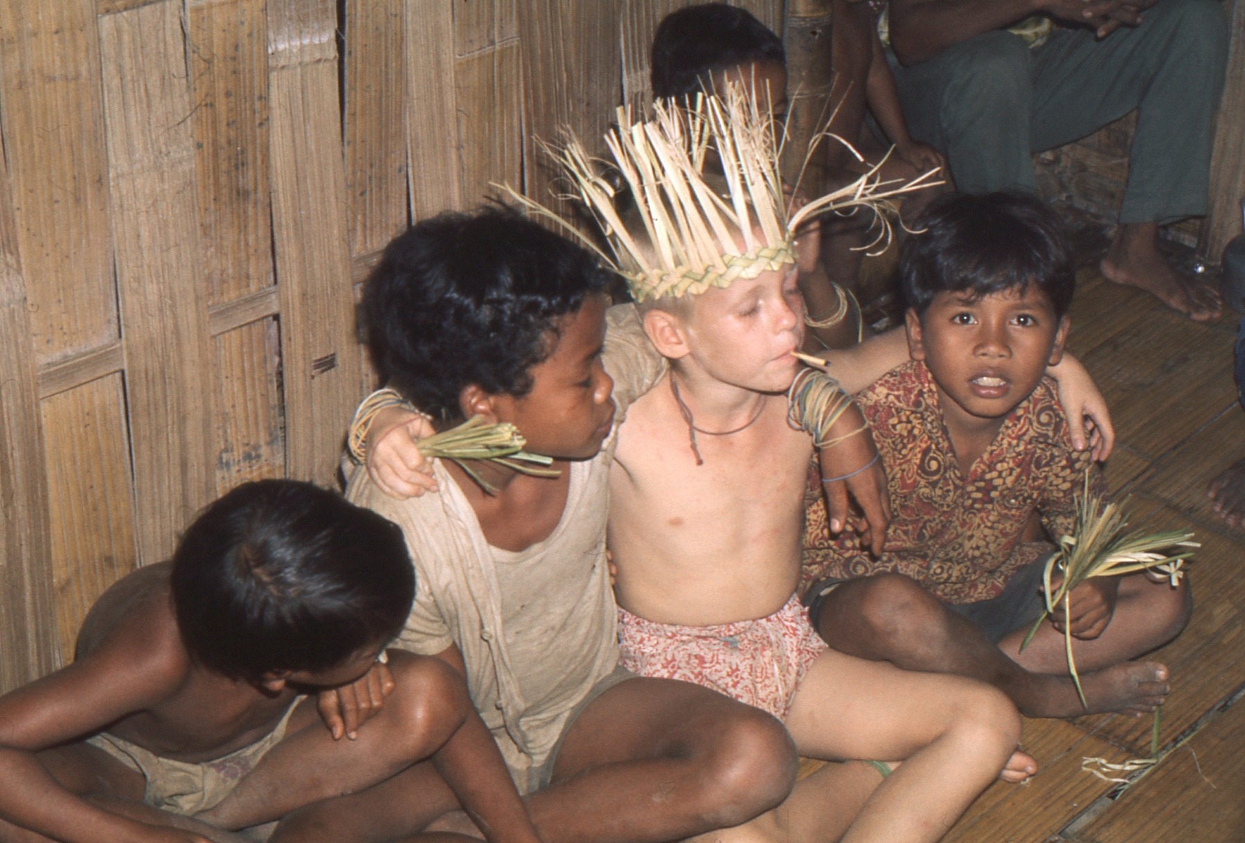 Andy’s brother sitting with three Temiar friends, wearing a woven leaf headpiece